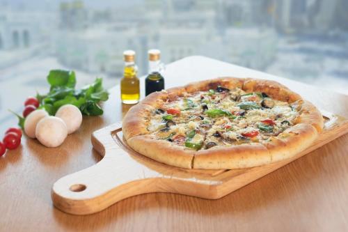 a pizza on a wooden cutting board on a table at InterContinental Dar Al Tawhid Makkah by IHG in Makkah