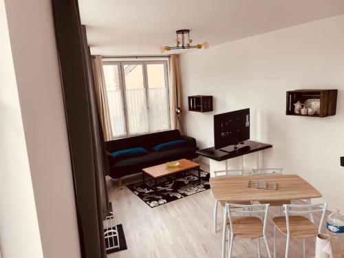 een kleine woonkamer met een tafel en een bank bij Superbe appartement à la croisée des 4 Châteaux in Lignières-de-Touraine