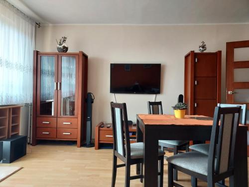 une salle à manger avec une table, des chaises et une télévision dans l'établissement Cozy Rooms Gdańsk, à Gdańsk