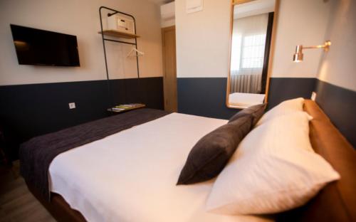 a bedroom with a white bed with pillows and a television at Urla 1867 Hotel in Urla