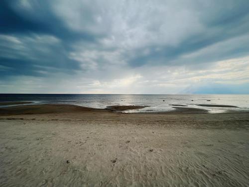 una spiaggia con cielo nuvoloso e l'oceano di Hailuoto Marjaniemi - Rantasumppu Cottage 9 with Sauna a Hailuoto