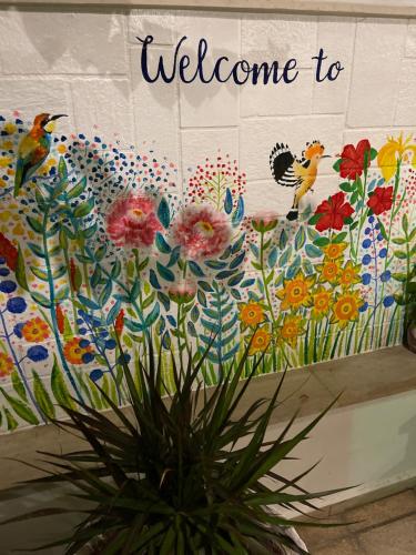 a wall with a welcome sign and flowers on it at Matala View in Matala