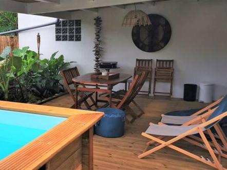 une terrasse avec une table, des chaises et une piscine dans l'établissement Cottage Tropical, à L'Étang-Salé