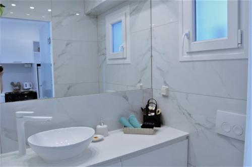ein weißes Badezimmer mit einem Waschbecken und einem Spiegel in der Unterkunft Asmini Studios in Pefki