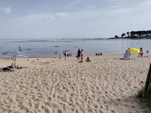 a group of people on a beach with umbrellas at Appartement T2 tout équipé à 100m de la mer in Saint-Philibert