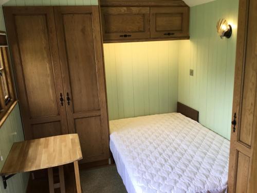 Dormitorio pequeño con cama y armarios de madera en The Homestead en West Parley