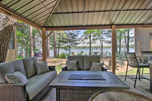 a screened in porch with a couch and a table at Loon Lake Lodge with Dock, Sauna and Hot Tub! in Pequot Lakes