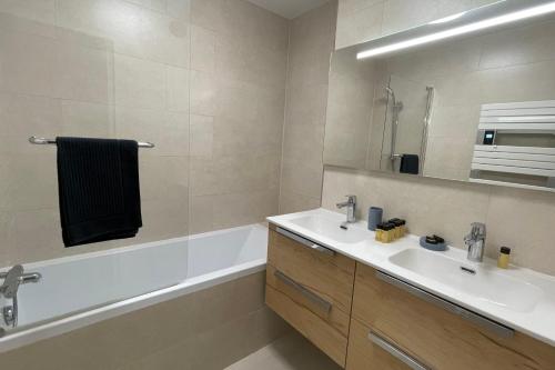 a bathroom with a sink and a tub and a mirror at Le Bois Gentil - Grand appartement familial, proche de Genève et du Palexpo in Saint-Julien-en-Genevois