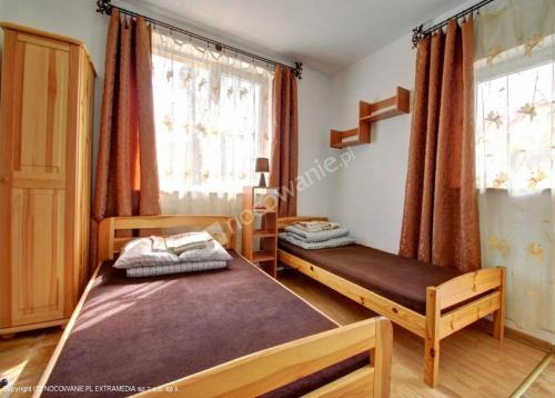 a bedroom with two beds and two windows at Jasionka 2 in Ustrzyki Dolne