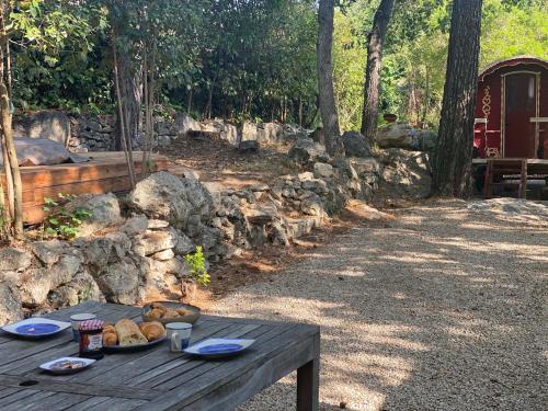 a picnic table with a plate of bread on it at Les roulottes de Bayama - logement insolite avec jacuzzi in Mougins