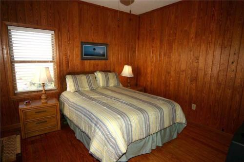 Un dormitorio con una cama con paredes de madera y una ventana en M.S. Whaley, en Edisto