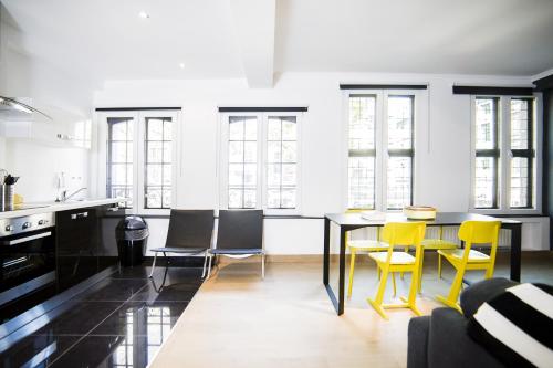 une cuisine avec des chaises jaunes et une table noire dans l'établissement Smartflats City - Perron, à Liège