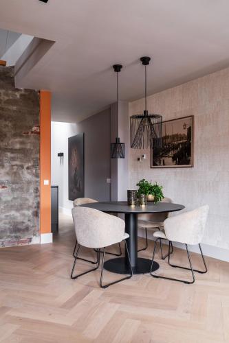 a dining room with a black table and white chairs at Luxe appartementen Havenzicht in Sint Annaland