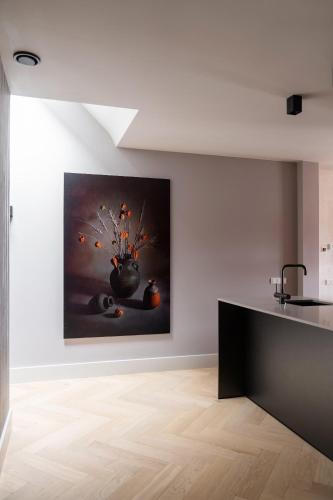 a kitchen with a painting of a vase with fruit at Luxe appartementen Havenzicht in Sint Annaland
