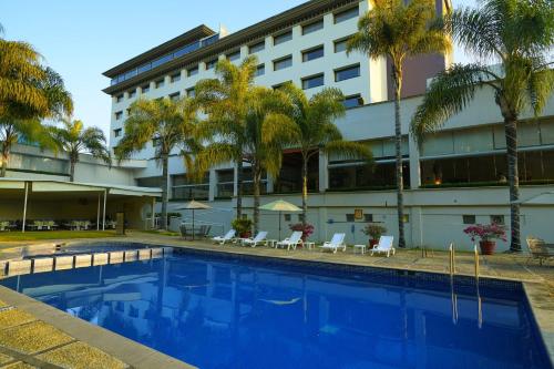 una piscina frente a un hotel con palmeras en Gamma by Fiesta Americ Xalapa Nubara, en Xalapa