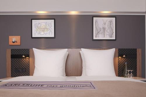 a bedroom with a bed with three pictures on the wall at Radisson Blu Hotel Karlsruhe in Ettlingen