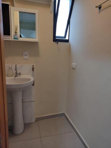 Un baño con lavabo y ventana. en Studio Aconchegante no Edifício Mirante do Vale - 200Mb, en São Paulo