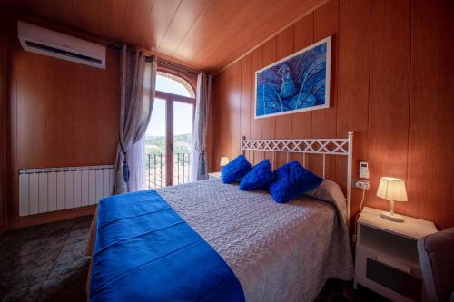 a bedroom with a bed with blue pillows and a window at Cassola Del Priorat in Gratallops
