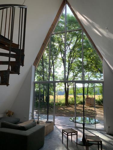 un salon avec une grande fenêtre en verre dans l'établissement La Maison Villeneuve - Lodges avec bains nordiques, à Donnay