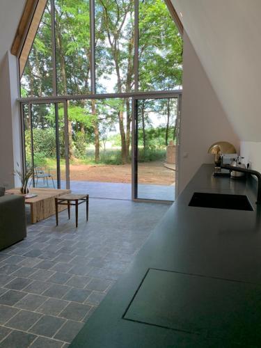 een woonkamer met een groot raam en een tafel bij La Maison Villeneuve - Lodges avec bains nordiques in Donnay