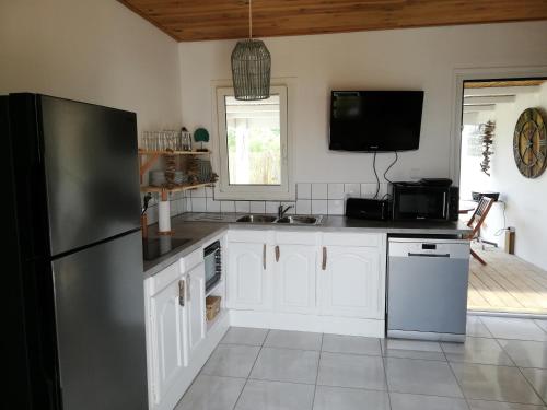La cuisine est équipée de placards blancs et d'un réfrigérateur noir. dans l'établissement Cottage Tropical, à L'Étang-Salé