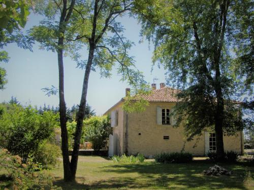 an old stone house with trees in the foreground at La Chartreuse in Larroque-Engalin