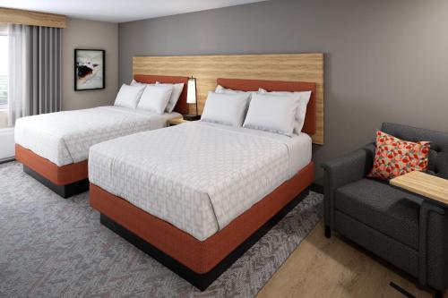 una habitación de hotel con 2 camas y una silla en Candlewood Suites Sheridan, an IHG Hotel, en Sheridan