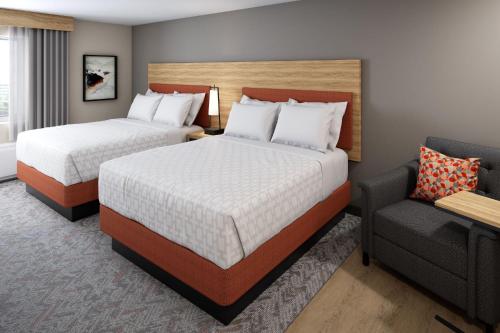 a hotel room with two beds and a chair at Candlewood Suites Sheridan, an IHG Hotel in Sheridan