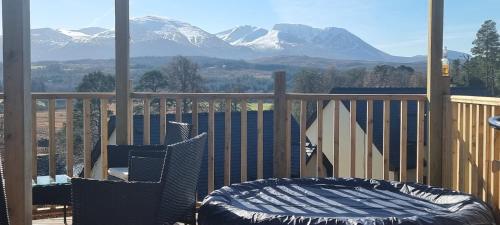 a balcony with two chairs and a bed and mountains at Nadurra But and Ben - Where the Ordinary Becomes Extraordinary in Fort William