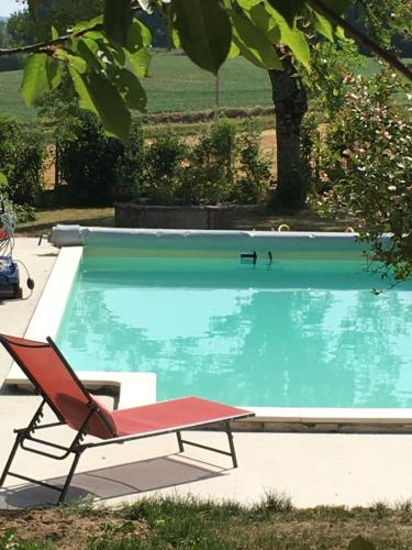 uma cadeira vermelha sentada ao lado de uma piscina em La Chartreuse em Larroque-Engalin
