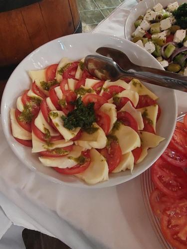 a white bowl of food with tomatoes and a spoon at Salaš Đorđević in Subotica