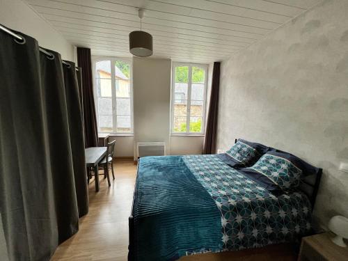 a bedroom with a bed and a table and windows at Ti Feunteun Pontrev in Pontrieux