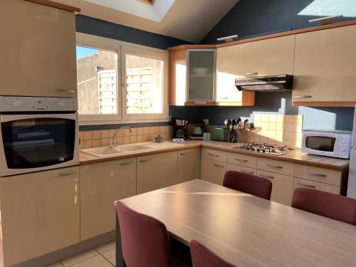 une cuisine avec une table et un comptoir dans l'établissement Maison de village avec jardin 15mn des plages, wifi, 2 chambres, jardin, à Hesdin-lʼAbbé