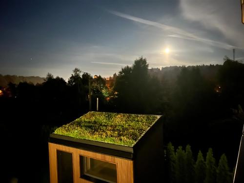 a building with a green roof with the sun in the background at Dom z basenem Bałtów 22 in Bałtów