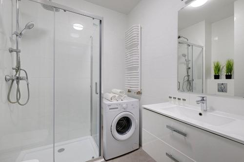 ein weißes Badezimmer mit einer Waschmaschine und einem Waschbecken in der Unterkunft 2Br Apt Strzelecka 24 with balcony in Warschau