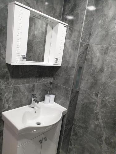 a bathroom with a white sink and a mirror at Apartment The Room in Burgas
