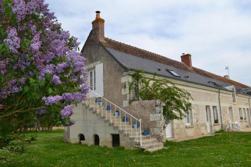 un bâtiment avec un escalier à côté d'un arbre aux fleurs violettes dans l'établissement Escale à Villeperdue chambre Hellulaug, à La Barillonnerie