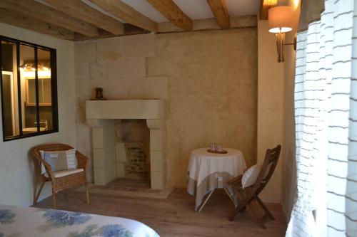 - une table et des chaises dans une pièce dotée d'une cheminée dans l'établissement Escale à Villeperdue chambre Hellulaug, à La Barillonnerie