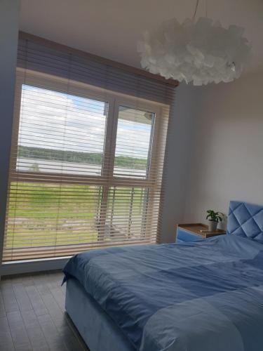 a bedroom with a blue bed and a large window at Apartament Pod Żaglami in Zegrze Południowe