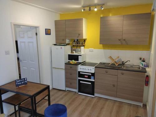 a small kitchen with a white refrigerator and a table at Cosy Flat in a Pretty Town. in Crewkerne