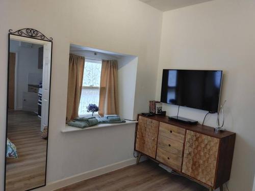 a living room with a flat screen tv on a dresser at Cosy Flat in a Pretty Town. in Crewkerne