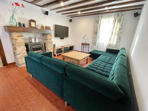 uma sala de estar com um sofá verde e uma lareira em La Foret em La Châtre-Langlin