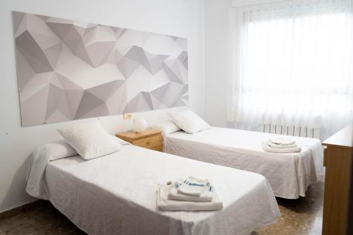 1 dormitorio con 2 camas y pared geométrica en APARTAMENTS ROIG, en Benasal