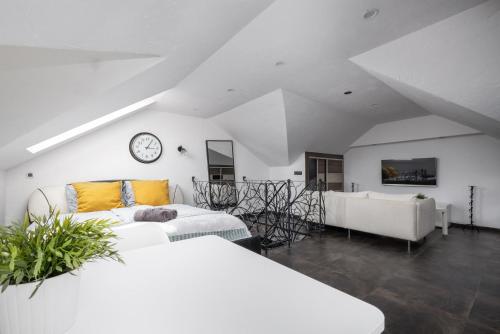 a white room with a bed and a couch and a clock at Villa Lordis in Krynica Morska