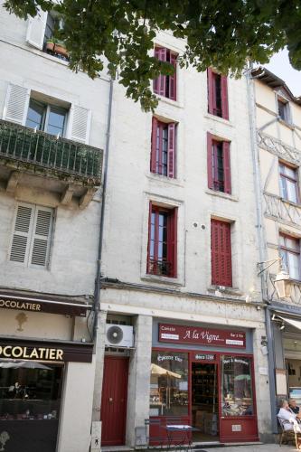 a tall white building with red windows on a street at Cœur historique classé in Périgueux
