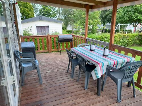 une table et des chaises sur une terrasse avec un grill dans l'établissement mobilhome 3 chambres, à Litteau