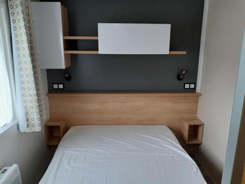 een kleine slaapkamer met een bed met een wit matras bij mobilhome 3 chambres in Litteau