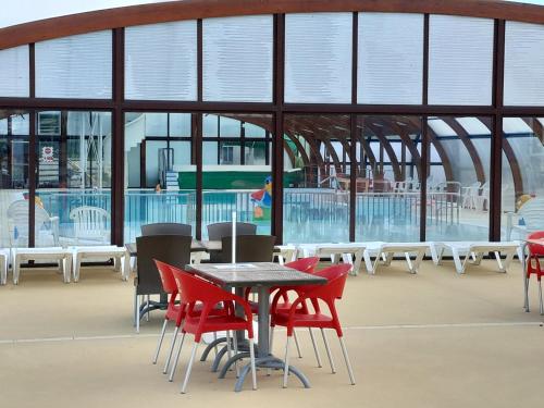 a table and chairs in front of a building with a pool at mobilhome 3 chambres in Litteau