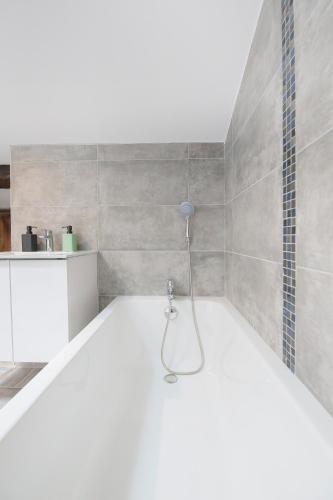 La salle de bains est pourvue d'une baignoire et d'une douche. dans l'établissement Le Classy, T3 hypercentre chic et cosy, Wifi par SOVALFI, à Saint-Étienne