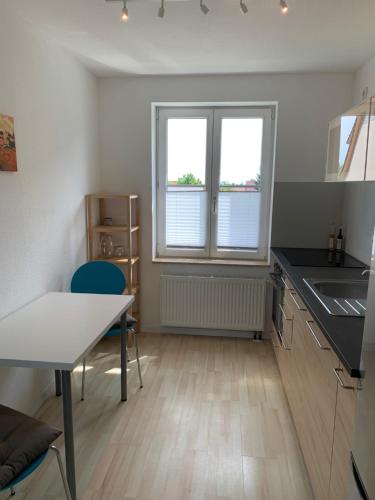 eine Küche mit einem Tisch, einem Waschbecken und 2 Fenstern in der Unterkunft Apartment Am Jakobsweg in Erfurt
